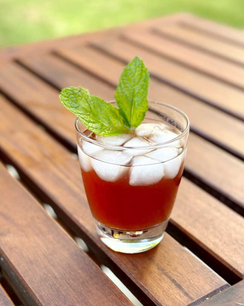 A refreshing green tea pomegranate drink for glowing skin served in a glass on a wooden table.